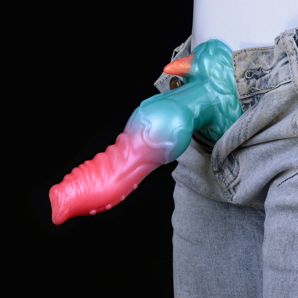 Teal-and-pink knotted alien dildo beside denim jeans, horned dog-like head