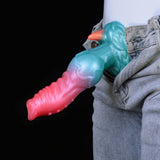 Teal-and-pink knotted alien dildo beside denim jeans, horned dog-like head