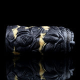Side view of the black textured dual-hole stroker with gold stripes and raised details