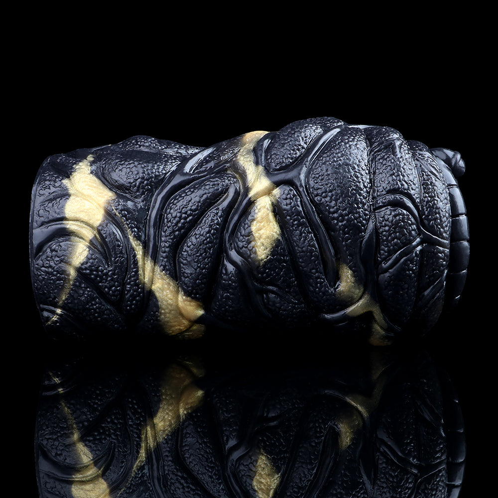 Angled view of the black textured vibrating stroker with gold accents and segmented grip