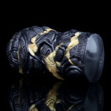 Head end of the black textured dual-hole stroker with gold streaks and embossed markings