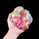 Iridescent flower-style G-spot grinder toy held in hand, textured petals