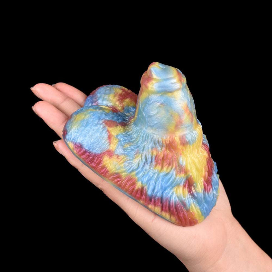 Rainbow plush sex toy held in hand, curved body and raised tip