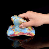 Hand holding multicolor tie-dye Sex Grinder Toy, heart-shaped form with molded curves
