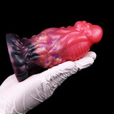 Alien butt plug in white glove: pink body, dark flared base, galaxy marbling