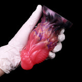 Gloved hold of pink alien anal plug with dark flared base and galaxy-pattern midsection