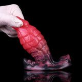 Pink dragon-scale anal plug held in gloves; close side profile