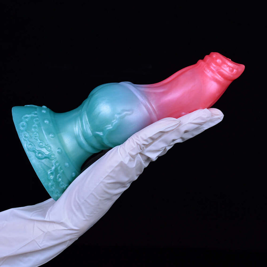 Pink-and-blue sex toy held by white gloves, resting on flared knot base