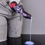 Gloved hand holds purple-and-red knot dildo with clear tube