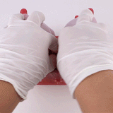Pink silicone anatomical toy with red detail held in gloved hands