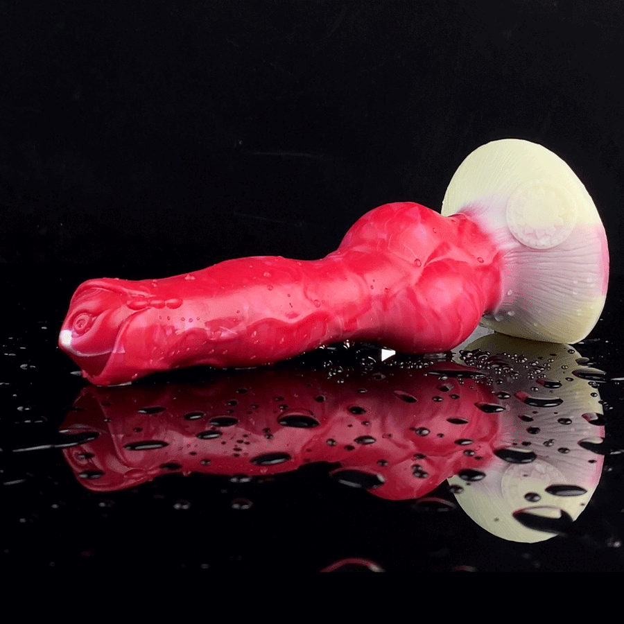 Red dog-shaped silicone adult vibrator with pale suction base, lying on its side.