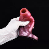 Pink glossy monster penis sleeve extender being held over gloved hand