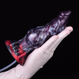 Gloved hand holding purple monster knot dildo with red base and clear tube