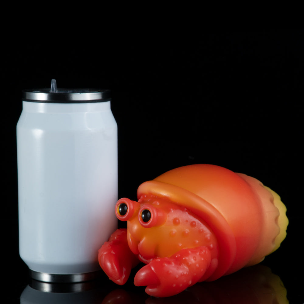Red-orange and yellow squeeze toy crab beside a white cylindrical cup