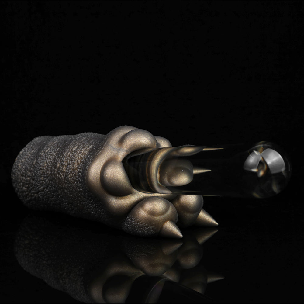 Bronze textured clawed hand reaching toward a small dark cylindrical object