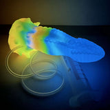 Glowing rainbow octopus vibrator on side, textured tentacles and clear tube