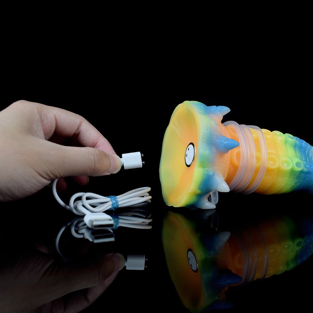 Hand holding octopus vibrator; glowing rainbow silicone and white charging cable