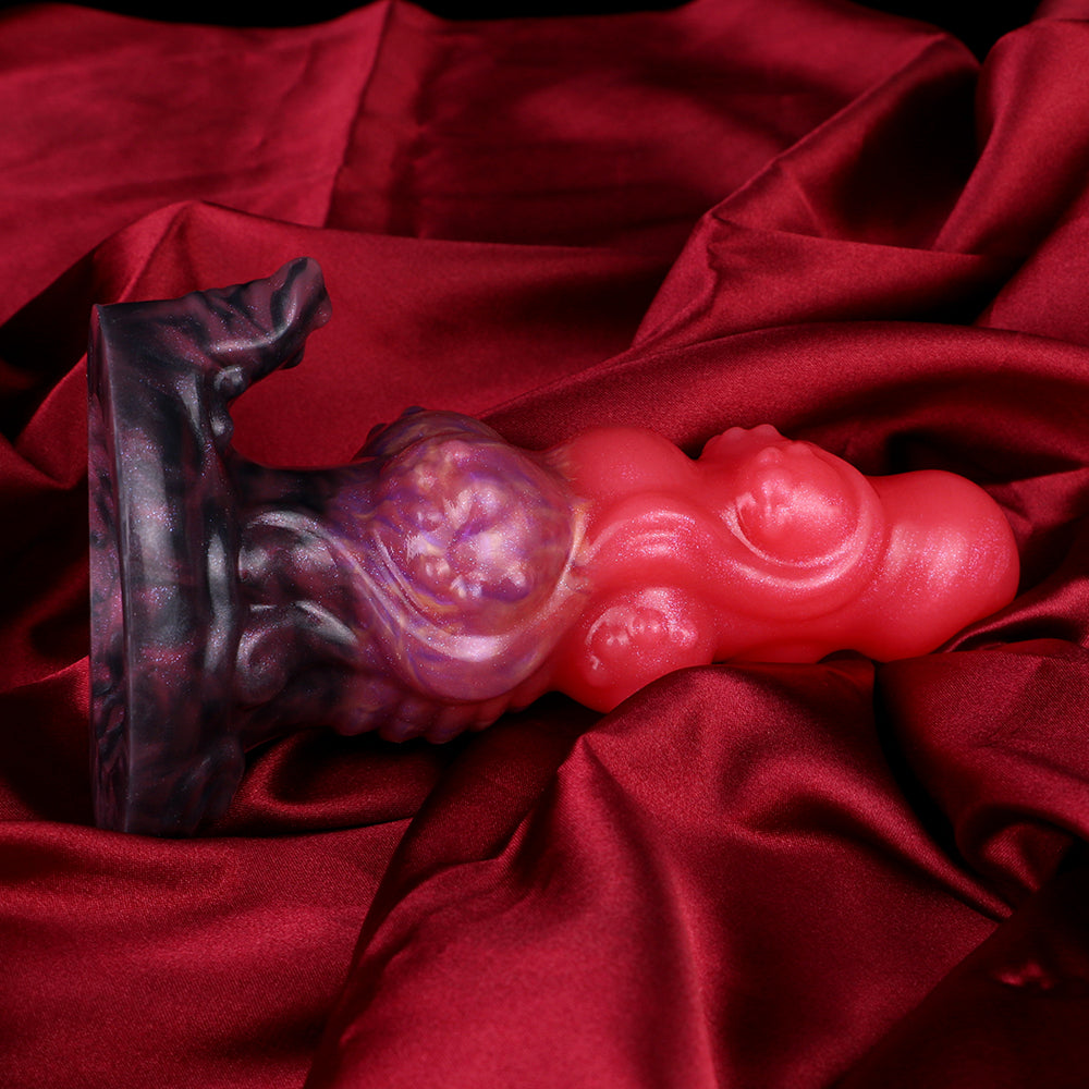 Alien anal plug on red fabric: glossy pink spiral body with purple swirl base