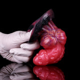 Gloved hand holding wolf butt plug; glossy pink body with dark tail base