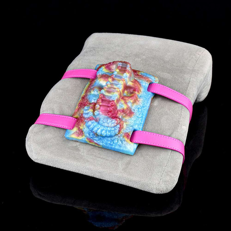 Rainbow octopus-pattern sex toy grinder with two pink straps on a gray cushion