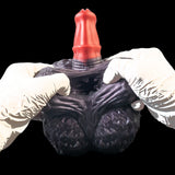 Purple textured hand-shaped toy with red horn top, held by white-gloved hands.