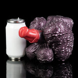 Purple textured creature toy with red forefinger, next to a white cylindrical can.