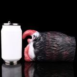 Creature toy resting beside white container; black fur exterior and pink ribbed opening
