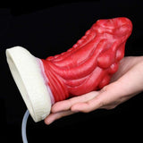 Red dragon anal plug with white base, hand holding from side and clear tube