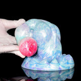 Close-up pastel blue dildo with red tip and knotted base, curved horn end.