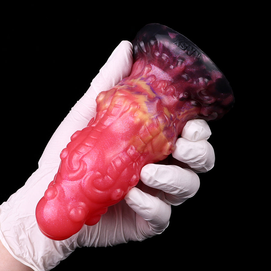 Ribbed alien butt plug held by gloved hand; glossy pink-red with dark purple tip