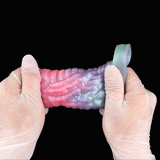 Dragon Cock Sleeve Extender zwischen Handschuhen gehalten, mehrfarbige Drachenform