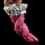 Close-up of pink textured octopus tentacle vibrator with hand on white base