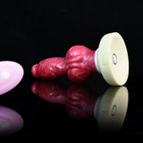 Red and pink silicone dog-knot butt plug with flared cream base, side view