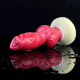 Wet red silicone dog-knot butt plug with flared cream base, side view