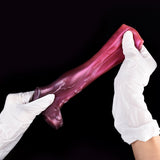 Octopus penis sleeve with maroon tentacle design, held by white-gloved hands