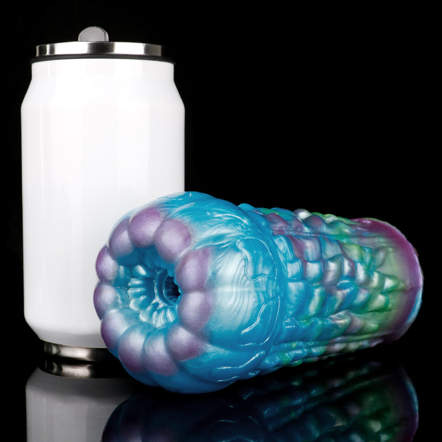 Iridescent alien-style male sex toy beside white base with metal ring connector