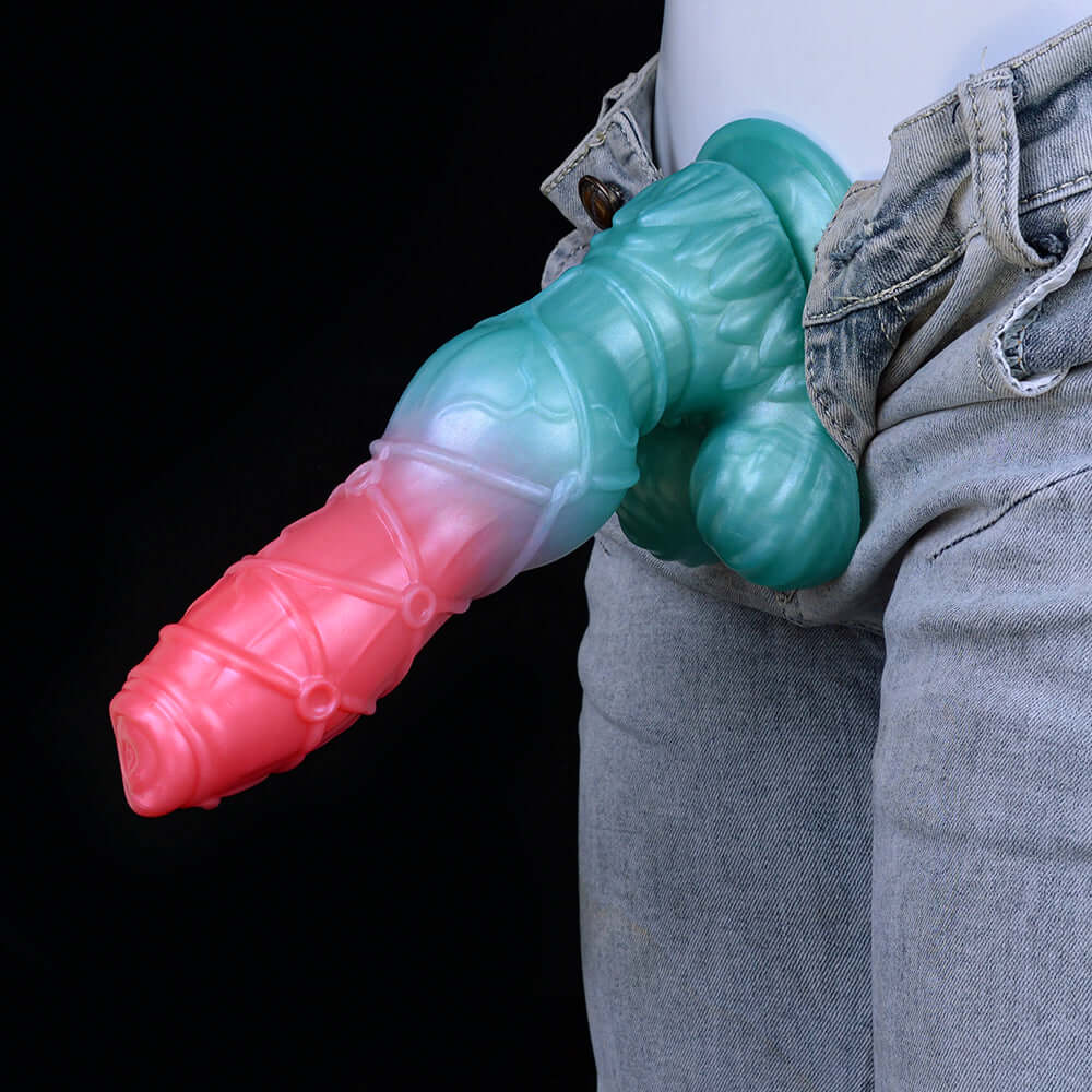 Blue and pink alien dildo tucked by denim jeans, ridged shaft and knotted base.