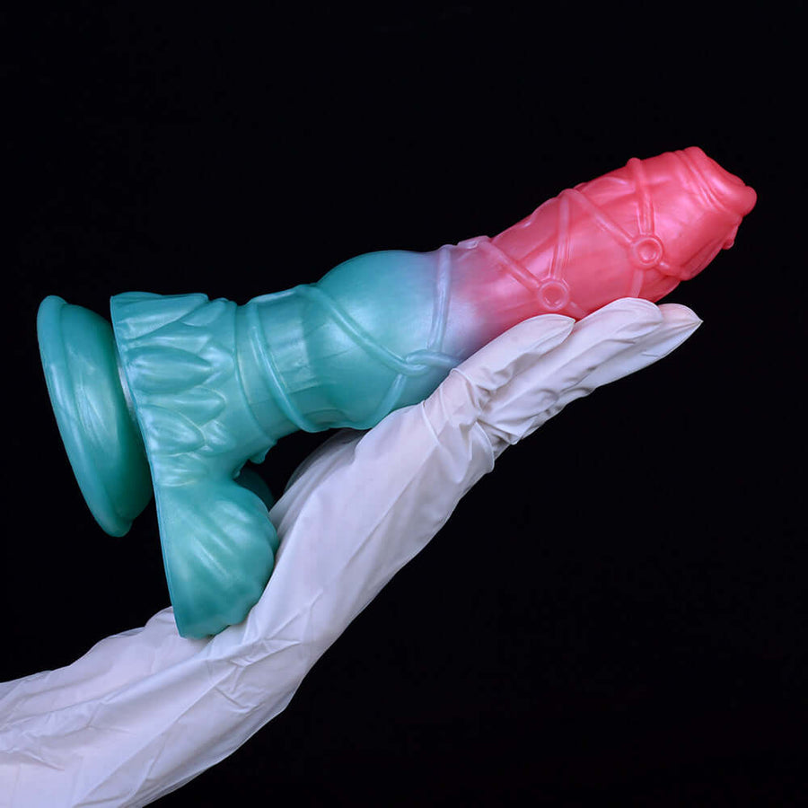 Teal-blue and pink knotted alien dog sex toy on white fabric, lying across