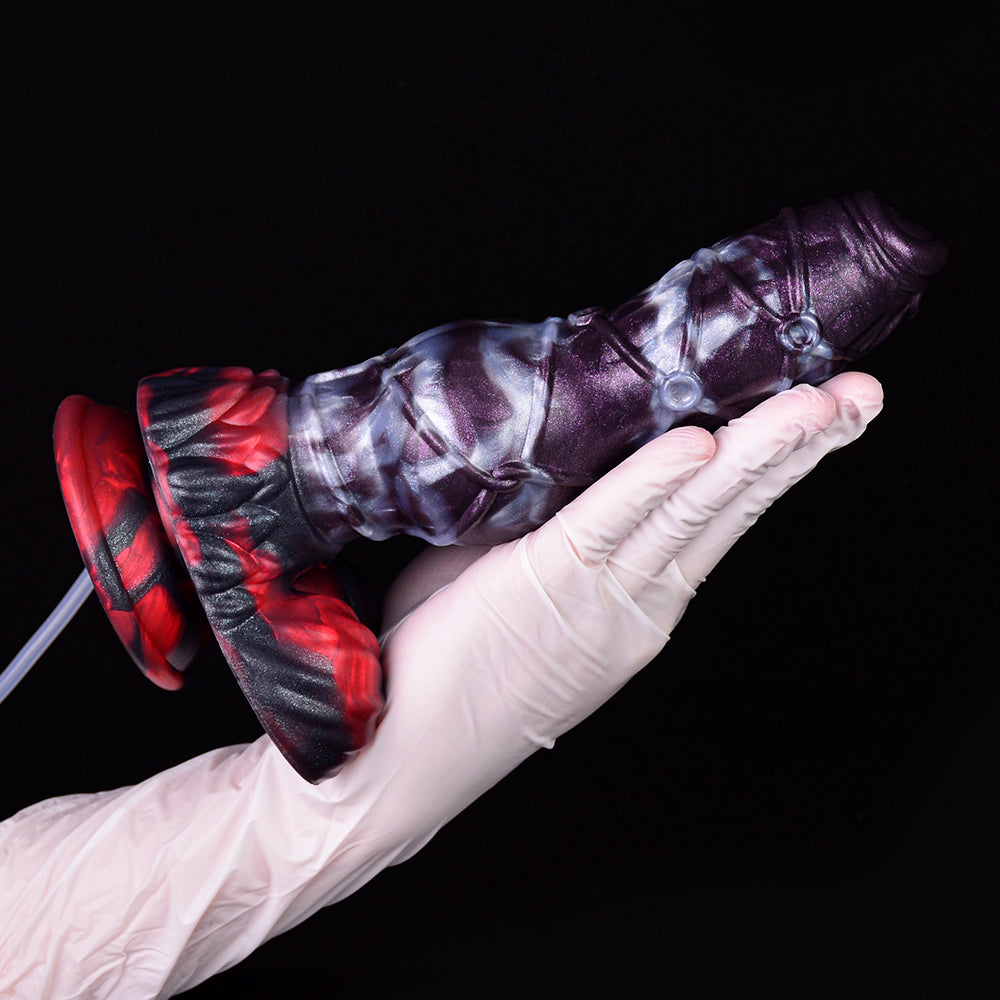 Gloved hand holding purple alien-themed squirting dildo with cum tube