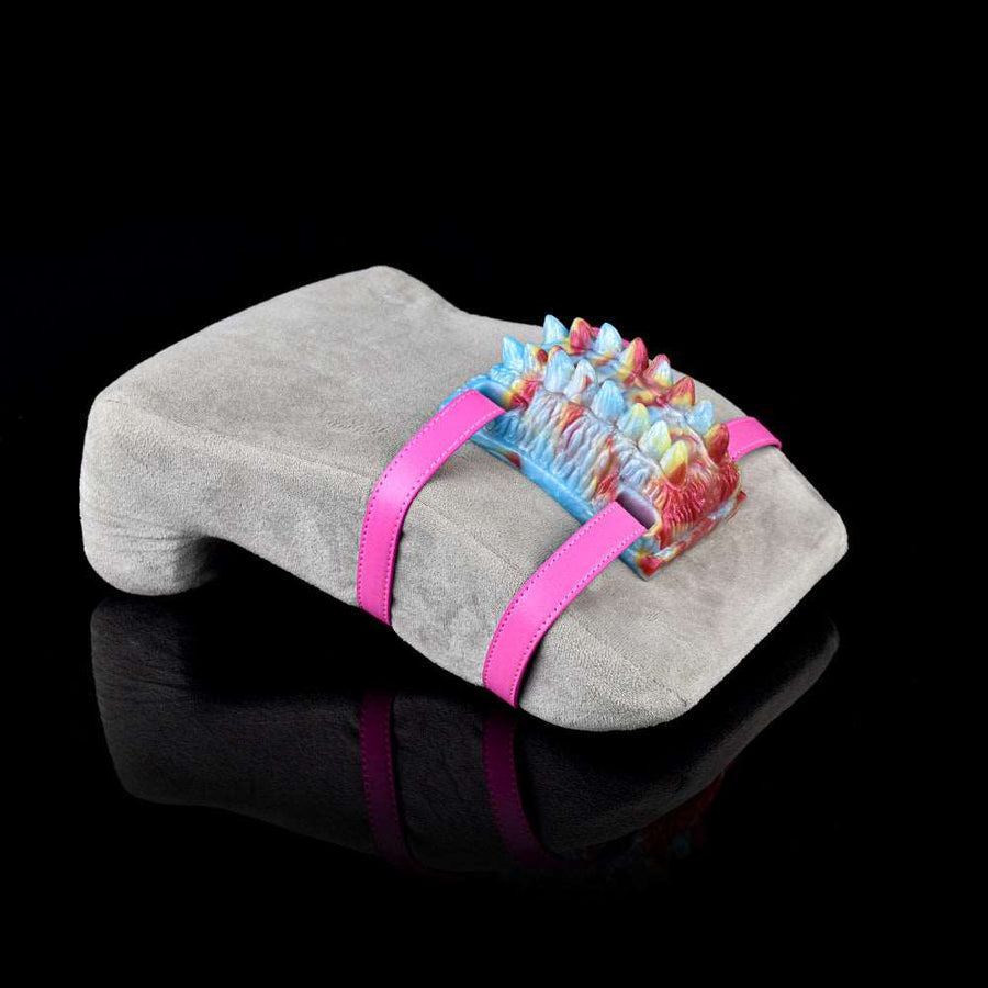 Gray fuzzy pad with pink straps holding a colorful textured vibrating grinder