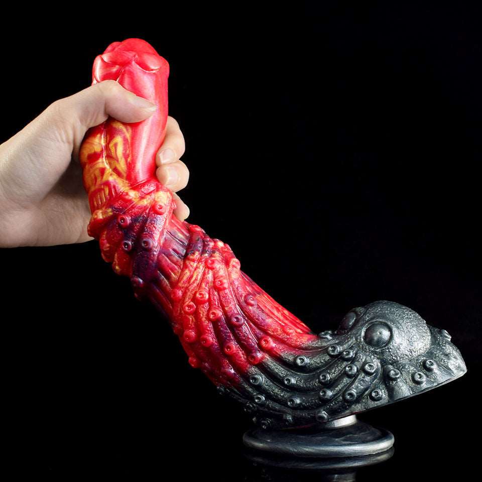 Red ribbed dragon dildo held in hand, curved design with dark metallic suction base