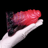 Dragon knot anal plug held with white glove; pink and purple with black knot base