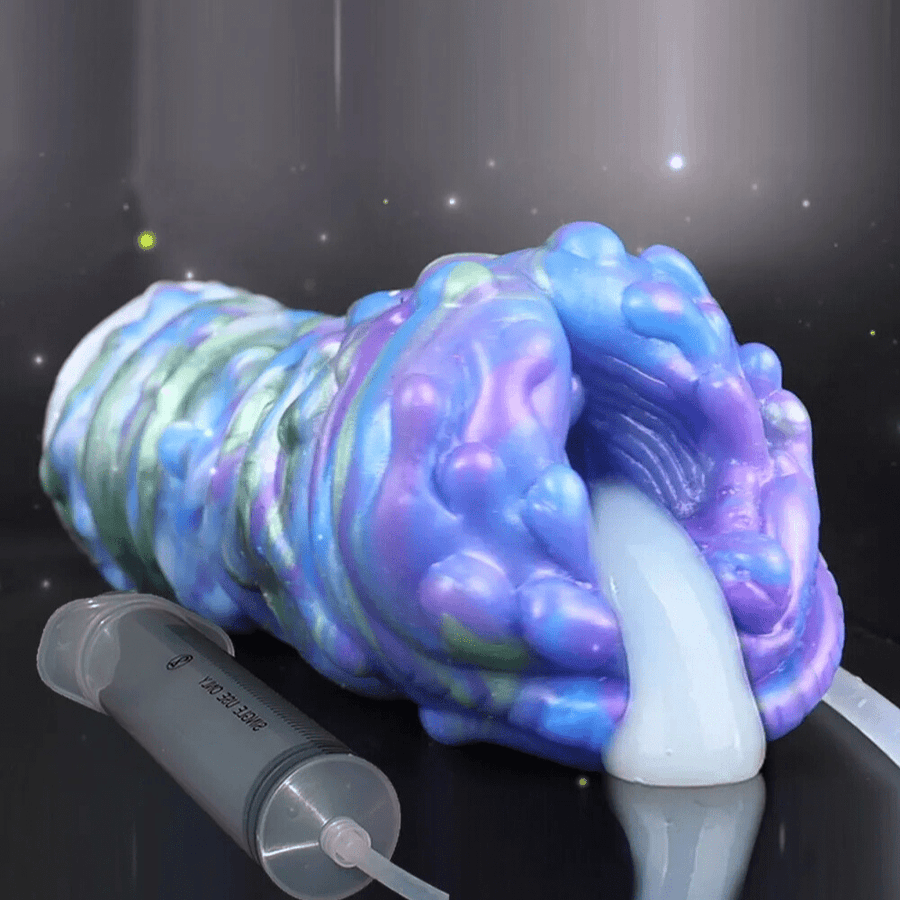 Colorful silicone stroker sleeve with bulbous head and attached nozzle, held on a dark base