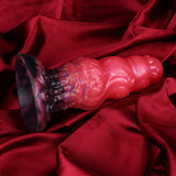 Alien butt plug on fabric; glossy red ribbed shape with dark purple flared base.