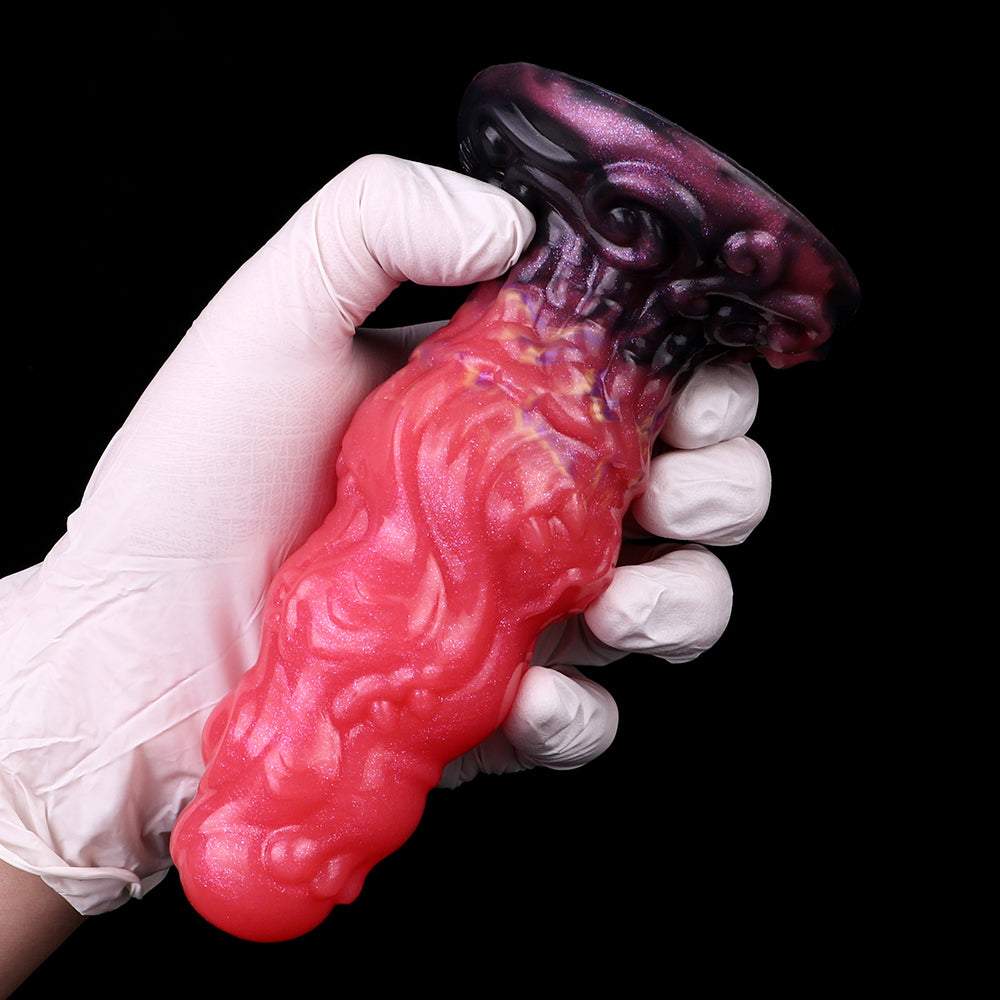 Alien butt plug in hand; glossy red ribbed body with dark purple ridged base.