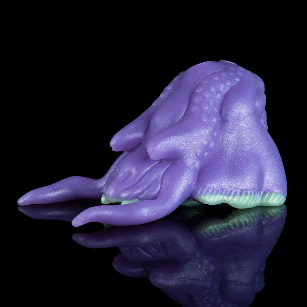Purple alien figurine lying on side with textured skin and curled forelimbs