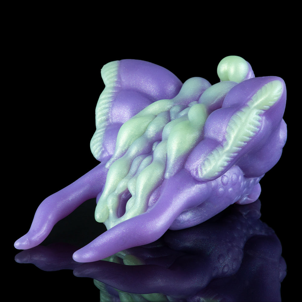 Purple and green alien figurine angled view with horned head and webbed legs