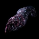 Metallic purple creature hand with clawed fingers and small blue eye detail