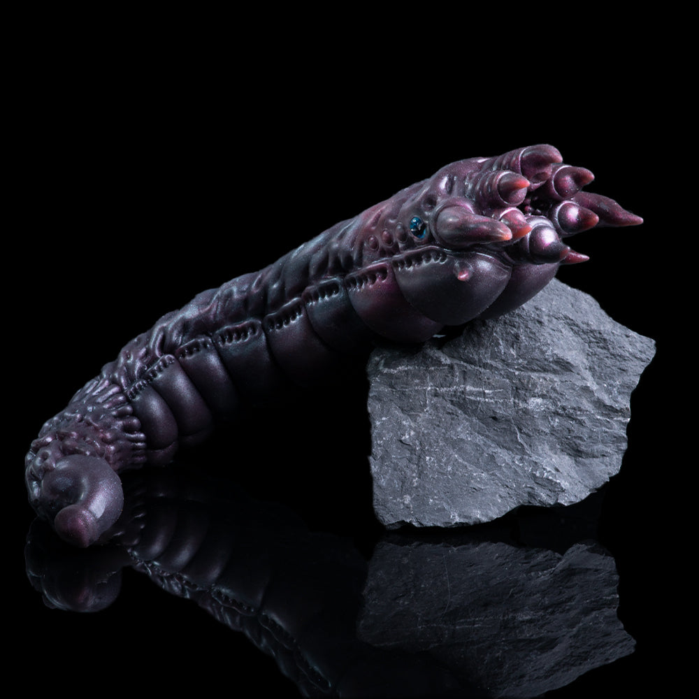 Metallic purple creature arm figure posed with clawed fingertips and blue eye