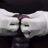 Purple alien creature toy held by white gloves, curled claws and glossy surface